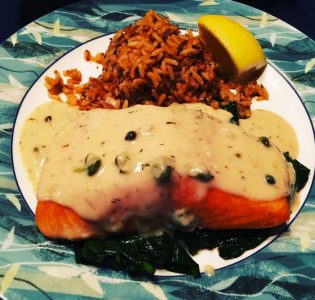 King salmon with lemon caper and dill cream served on top of sauteed spinach and rice