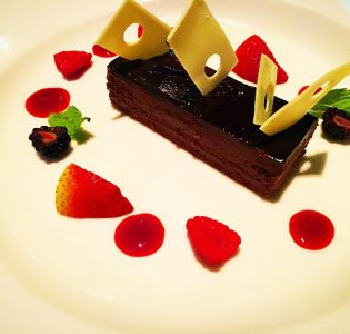 Chocolate emulsion cake with chocolate ganache, raspberry sauce